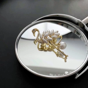 Elegant flamingo brooch with white faux pearls and cubic zirconia on mirror background