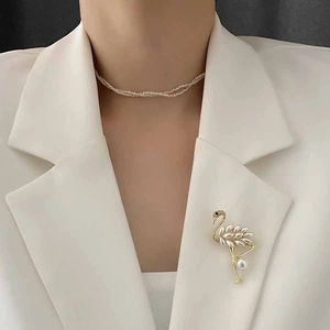 Elegant gold flamingo brooch with pearl feathers pinned on a white suit lapel