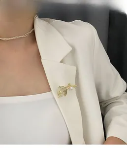 Détail d'une broche en opale avec perle blanche et diamants sur une veste de costume blanche