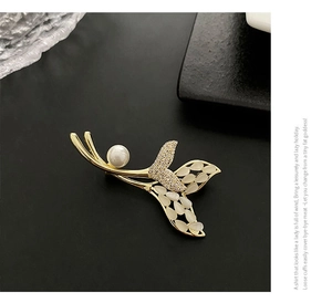 Vue macro d'une broche queue de poisson avec perle, zircons et ailes d'opale