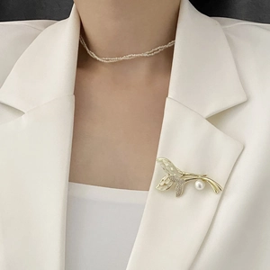 Broche élégante en œil de chat et perles sur une veste de tailleur blanche