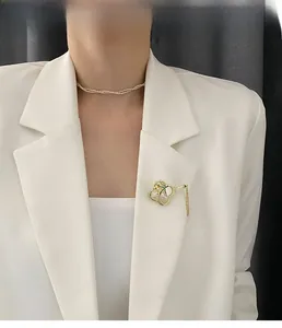 Modell mit goldener Fächerbrosche mit Quasten und Perlen-Choker auf weißem Blazer