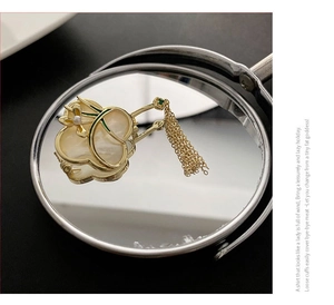 Detail einer eleganten Gold-Orchideenbrosche mit Perlmutt-Inlay und Quaste auf Spiegel