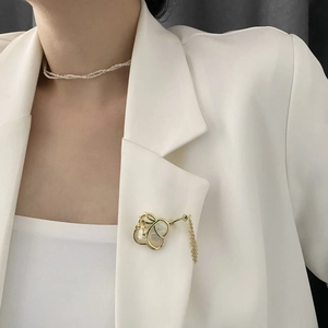 Elegante goldene Orchideen-Brosche mit Perlmutt-Blüten und Quaste auf einem Anzug