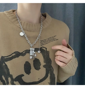 Silberne Chunky-Kette im Hip-Hop-Stil mit Fu-Zeichen und Herzanhänger auf beigem Pullover