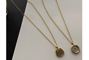 Detail of vintage gold coin pendants featuring elephant relief and queen head on thin chains