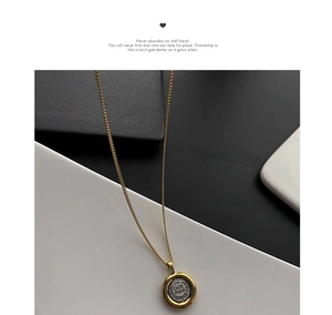 Close-up of gold coin necklace featuring a two-tone 1998 Dos Pesos pendant on a gold chain