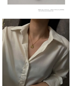 Close-up of golden coin necklace featuring an embossed cherub on an elegant model