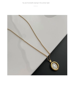 Detail of vintage gold-plated necklace with an oval coin pendant featuring Elizabeth II