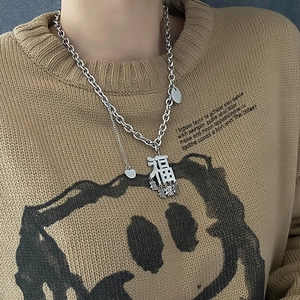 Hip-Hop Silberkette mit Fu-Charakter-Anhängern getragen auf einem kamelfarbenen Pullover