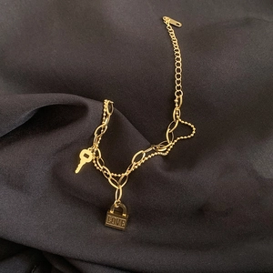 Goldenes zweilagiges Kettenarmband mit Schlüssel und LOVE Schloss auf schwarzem Stoff