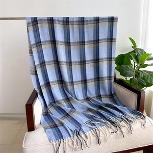 Close-up of blue and grey checkered scarf with long tassels on a cozy armchair