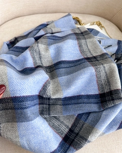 Close-up of classic blue and grey checkered scarf with soft cashmere-like fringe detail