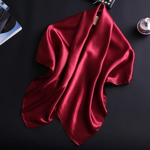 Gros plan sur un foulard en satin rouge foncé, texture soie et bords ourlés fins