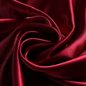 Vue détaillée du tissu satin de soie rouge foncé brillant avec texture ondulée
