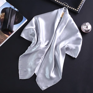 Gros plan d'un foulard en satin gris argenté suspendu à un cintre en bois chic