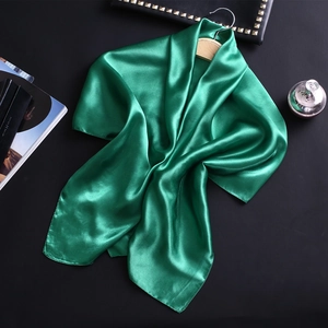 Texture détaillée du foulard en satin de soie vert émeraude drapé sur un cintre en bois