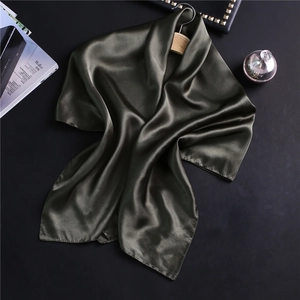 Détail d'un foulard en satin vert olive foncé avec cintre en bois sur fond noir chic