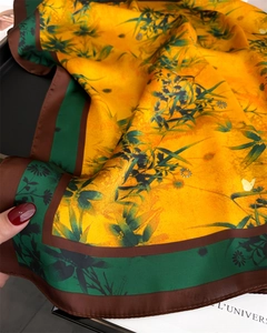 Detail of silk scarf showing green bamboo leaves and butterfly on orange fabric