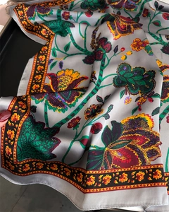 Close-up of vintage floral silk scarf featuring exotic plant prints and orange geometric borders