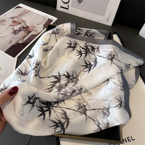 Close-up of silk-like scarf featuring elegant bamboo ink print and deep gray hemmed edges