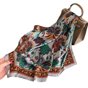 Vintage floral paisley silk scarf in grey with colorful patterns on a leather bag