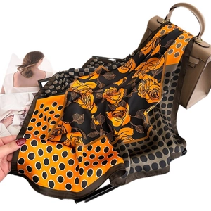 Polka dot and rose floral silk scarf tied to a leather handbag on a fashion magazine background