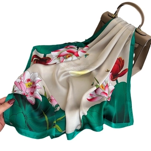 Elegant silk-like scarf with lotus flower prints draped on a luxury handbag