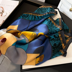 Close-up of a 70cm silk scarf with tropical leaf prints and abstract geometric patterns