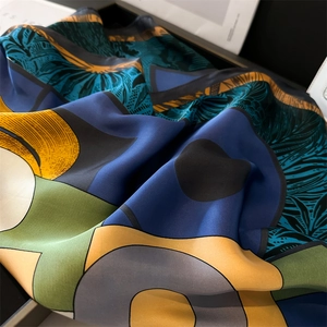 Detailed close-up of geometric color block faux silk scarf with elegant leaf patterns