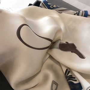 Close-up of luxury satin square scarf with equestrian patterns and golden ring hardware