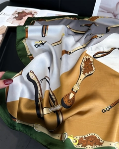 Detailed macro shot of vintage horse bridle patterns on silky green square scarf