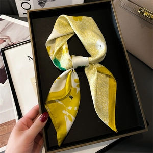 Détail d'un foulard en soie jaune à fleurs noué avec élégance dans un plateau satiné