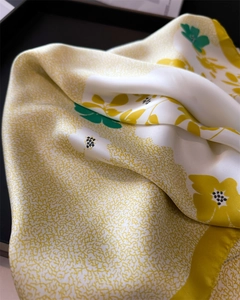 Détail d'un foulard en soie montrant la texture lisse et les motifs de fleurs jaunes