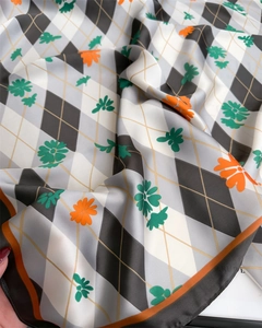 Détail d'un foulard en soie à carreaux avec imprimé marguerites et bords contrastés
