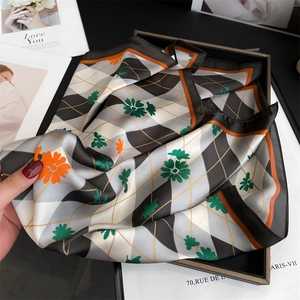 Détail d'un foulard en soie avec motif en losanges et imprimé floral de marguerites