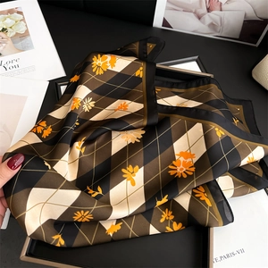Détail d'un foulard carré en soie avec motif en losanges et marguerites oranges en coffret