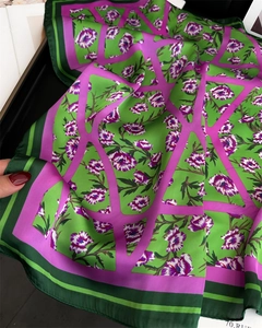 Détail de la texture d'un foulard en soie verte avec motifs floraux violets et lignes géo