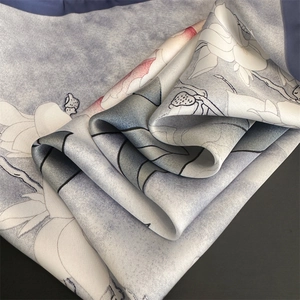 Detail of silk scarf showing lotus floral patterns and elegant gray-purple gradient fabric