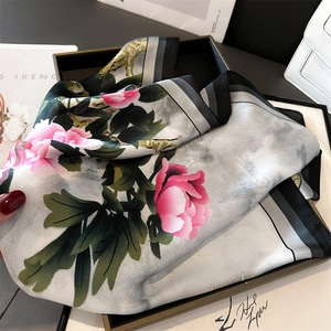 Detail of peony print silk scarf with floral patterns on a black display tray