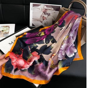 Detailed macro view of floral silk scarf draped over a classic leather handbag
