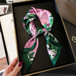 Detail of silk scarf with pink floral patterns and green borders on a stylish display