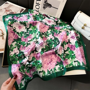 Detailed view of square silk scarf featuring floral prints and dark green border design