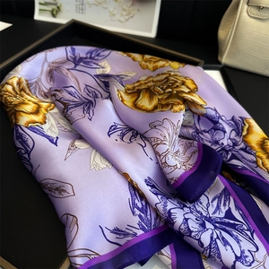Detailansicht eines lila Seidentuchs mit gelbem Blumenmuster auf einem schwarzen Tablett
