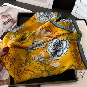 Detail eines Seidenschals mit Blumenmuster in Gelb und Blau, elegant präsentiert