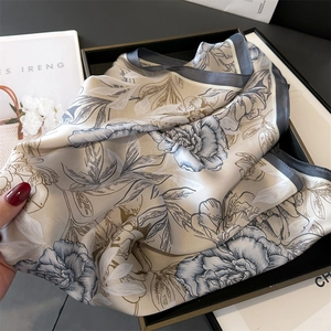 Makro-Detail des Seidenschals mit Pfingstrosen-Print und Satin-Textur in einer Geschenkbox