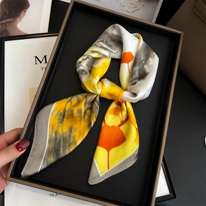Détail du foulard en soie jaune avec feuilles de ginkgo orange et bordure grise fine