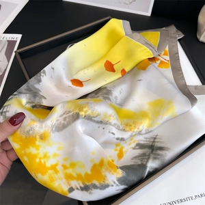 Détail des motifs de feuilles de ginkgo jaunes et texture de soie lisse du foulard