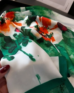 Détail d'un foulard en soie avec motifs de fleurs à l'huile verts et bords bien finis