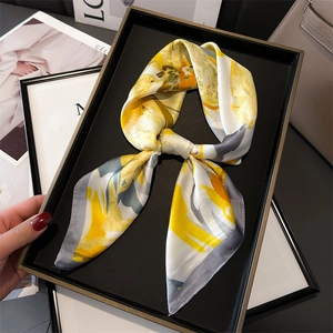 Détail d'un foulard en soie aux fleurs peintes à l'huile en jaune et gris sur un plateau